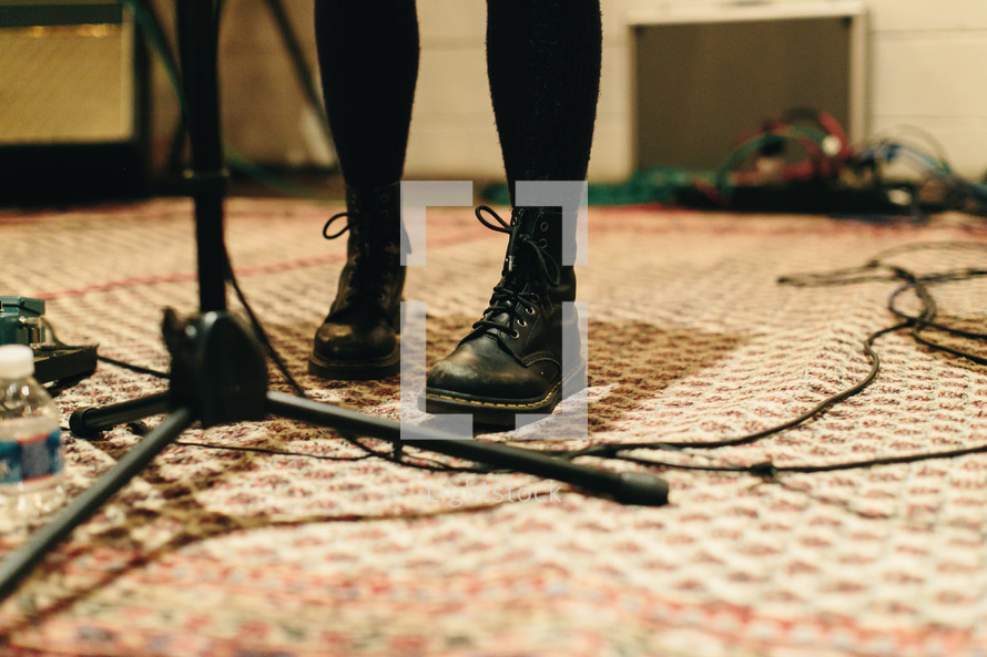 feet standing beside of a microphone stand 