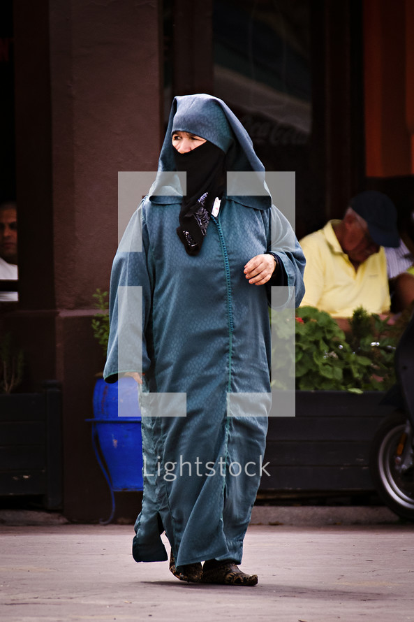 covered muslim woman walking on the streets 