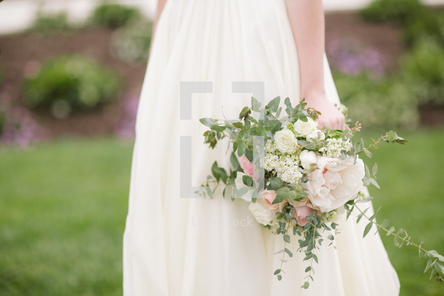 torso of a bride holding a bouquet 