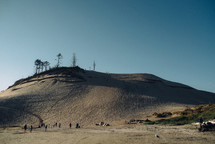 people at the bottom of a large sand dune 