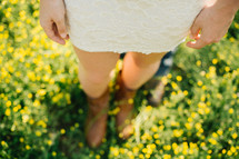 a woman standing in a meadow of yellow spring flowers 