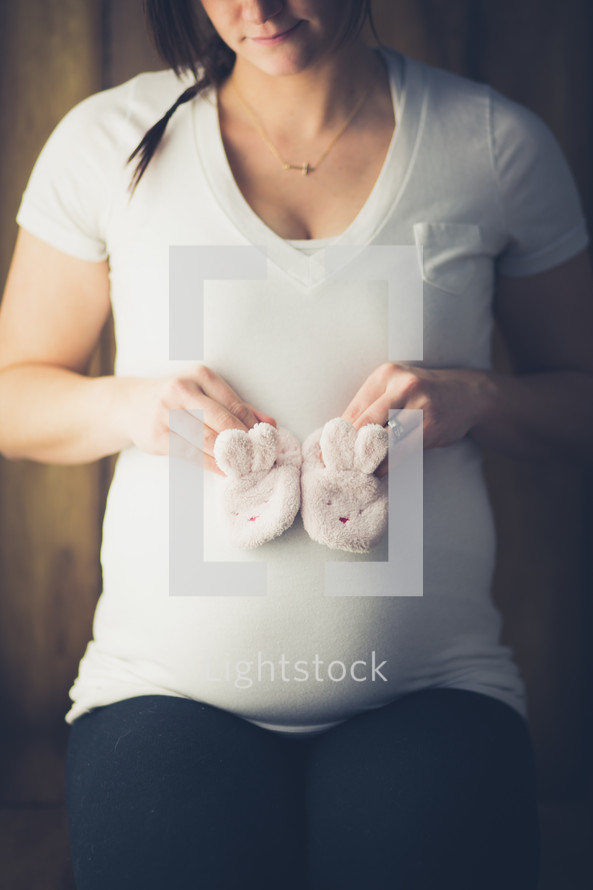 Expecting mother holding a pair of baby booties.