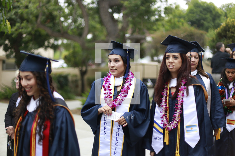 graduates in a cap and gowns and Hawaiian leis