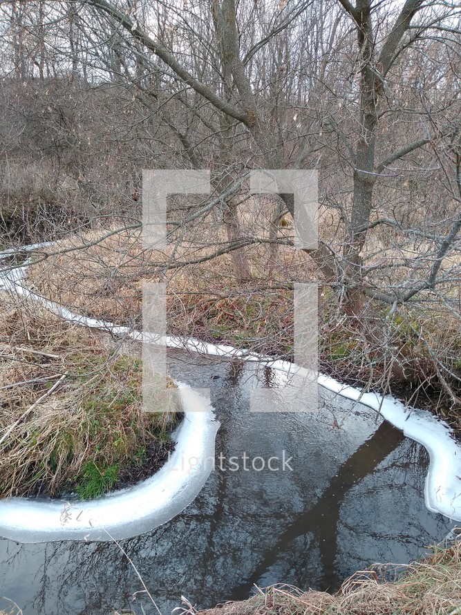 Winding, icy creek with bare trees