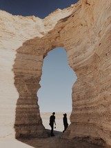 men standing in a rock arch 