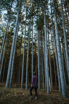 woman in a plaid shirt walking through a forest 