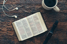 earbuds, smartwatch, Bible, and coffee cup 