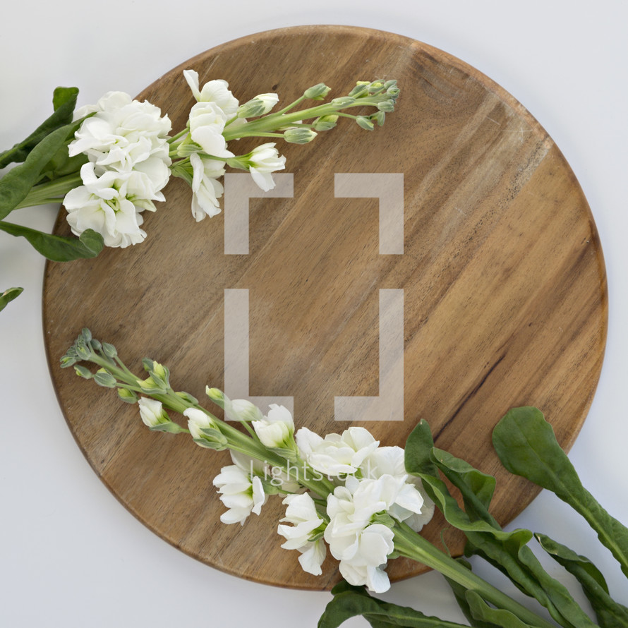 white flowers on a cutting board against a white background 