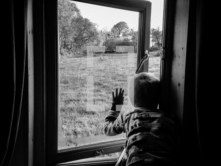 a toddler boy looking out a window 