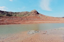 a lake and red rock cliffs