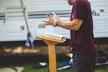a man preaching at a podium outdoors 