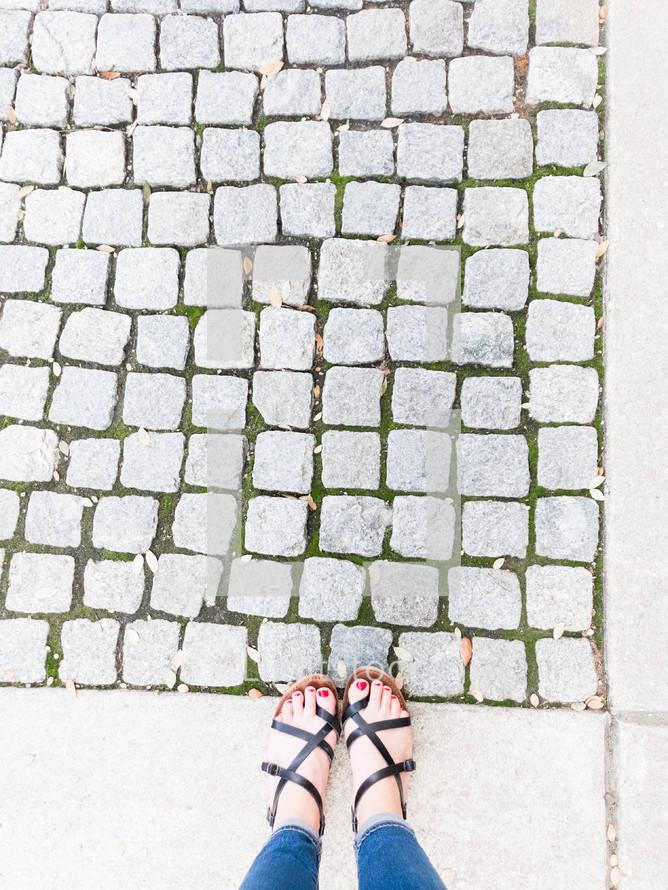 feet in sandals and cobblestone sidewalk 