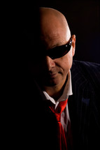 Bald man wearing sunglasses and suit