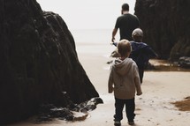 father and sons exploring a beach in fall 