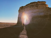 a man walking through a rock formation in a desert at sunset 