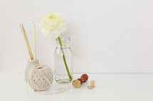 white flower in a clear vase, pencils, yarn, and stamp 