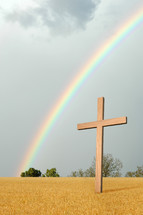 rainbow over a wheat field and a cross