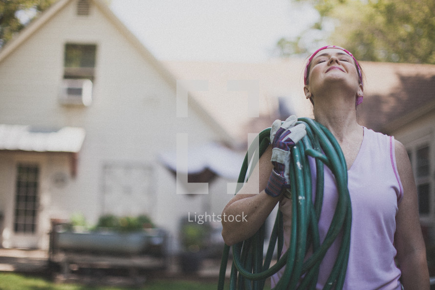 woman carrying a hose and looking up