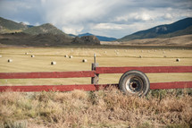 fence in front of a field and hay bales 