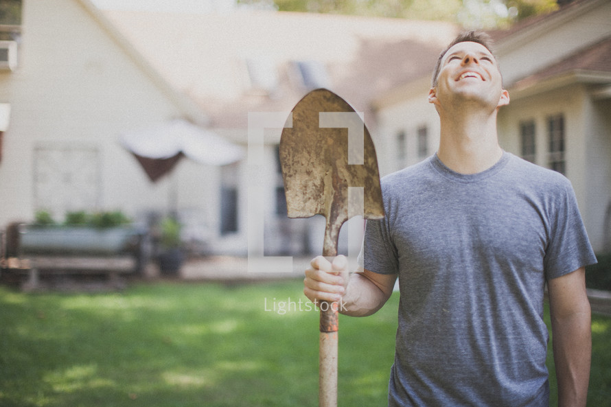 man holding a shovel and looking up to God