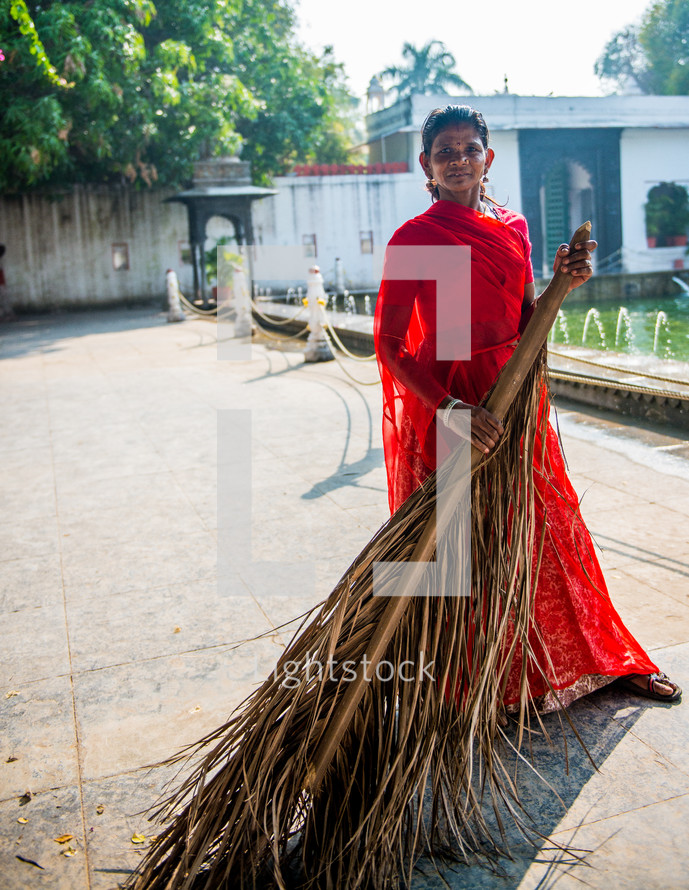 a woman sweeping with a palm frond in India 