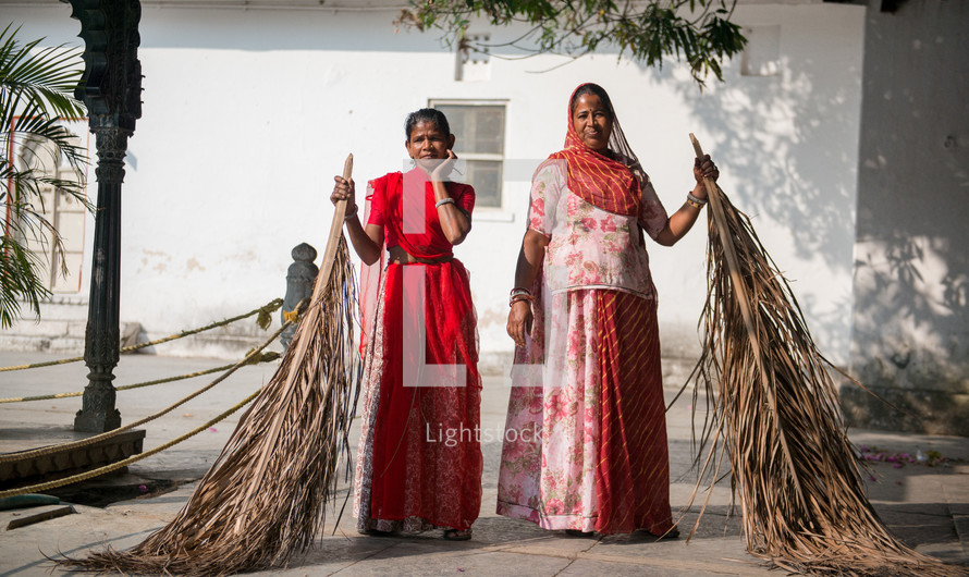 women sweeping in India with palm fronds 