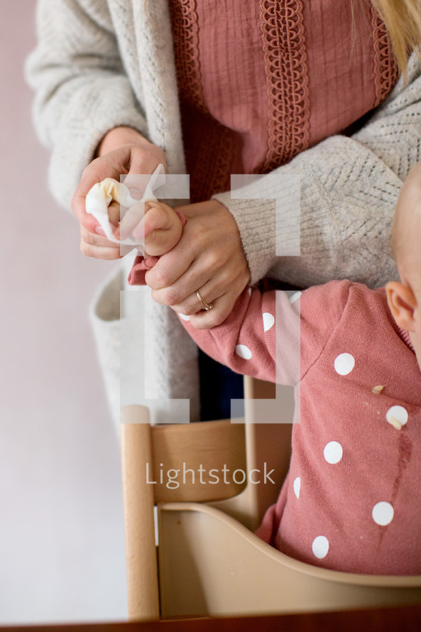 Mother cleaning baby's hands after lunch time 