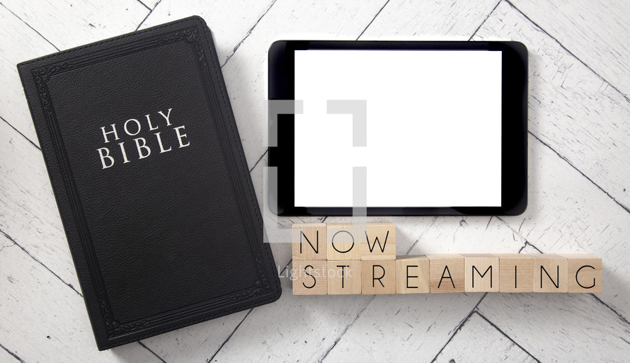 Bible and tablet on a white wood background - now streaming 