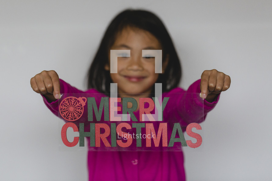 girl holding a Merry Christmas sign 