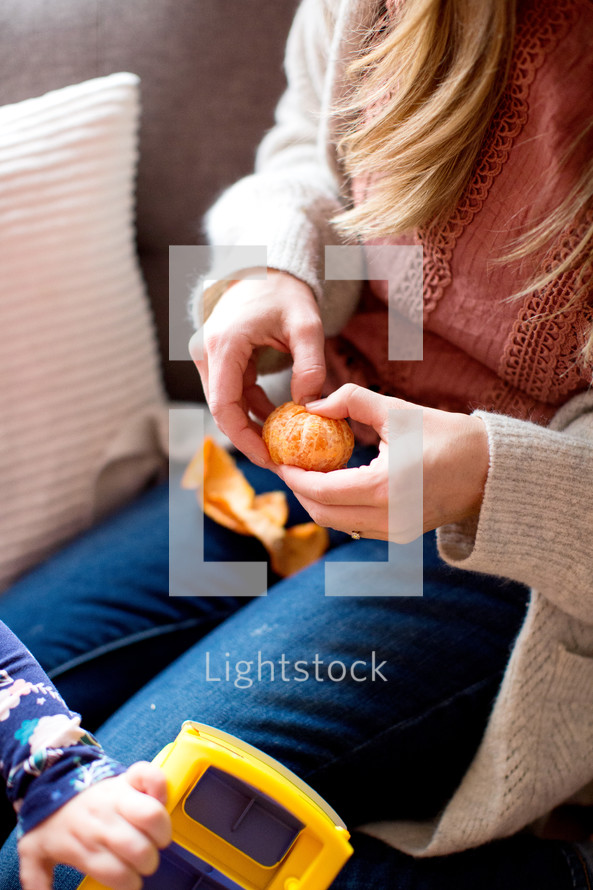 Mother's hands peeling an orange 