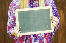 a woman holding a blank chalkboard sign 