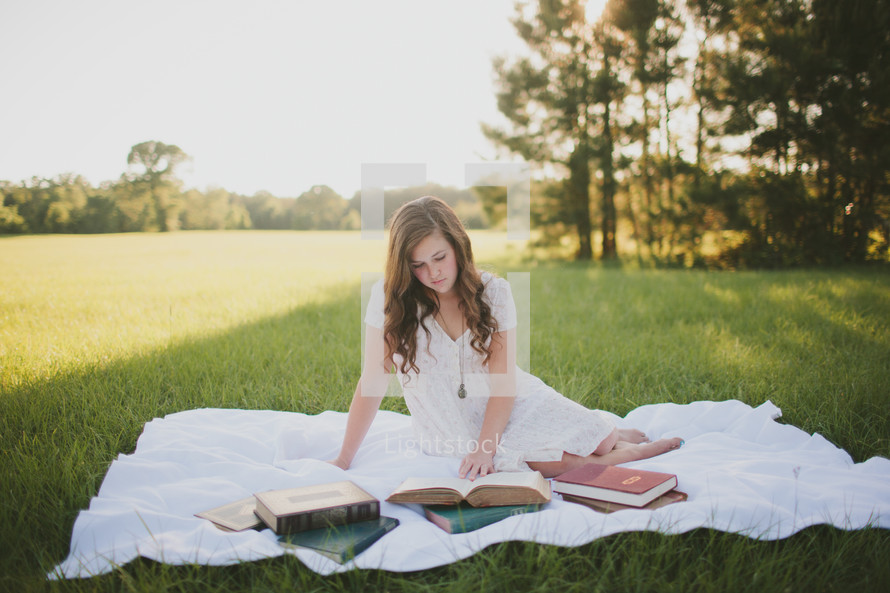 woman lying on a blanket in the grass reading