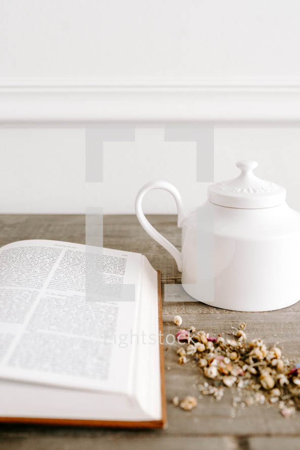 opened Bible on a table and tea pot