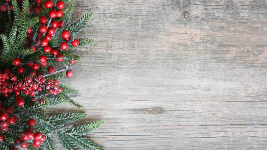 Christmas Holiday Season Background with Red Berries and Greenery Over Wood