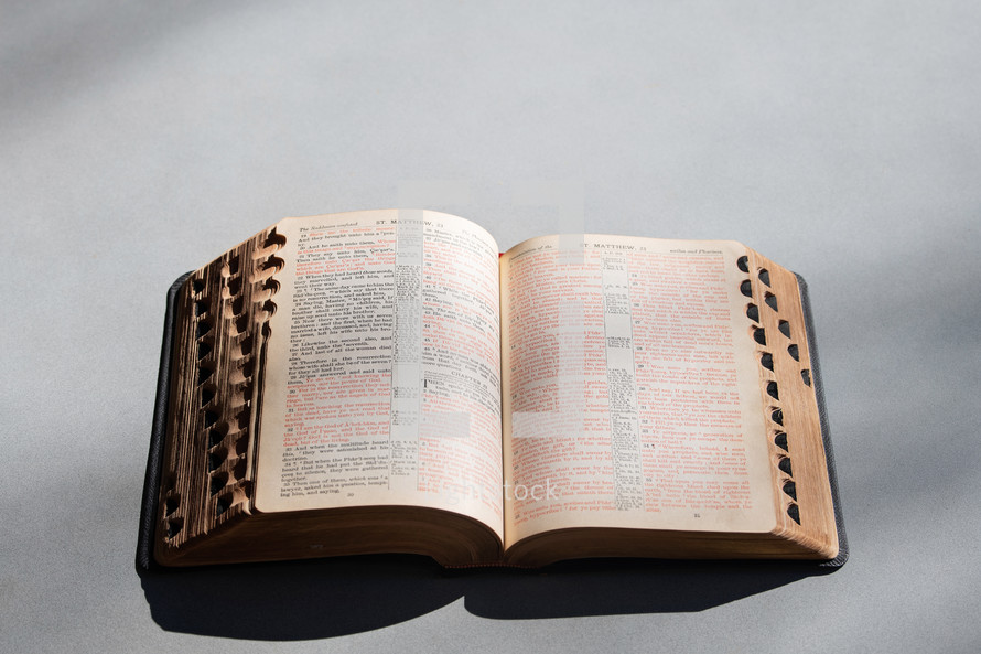 Open Bible with shadows on a grey table