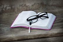 reading glasses on the pages of an open Bible 
