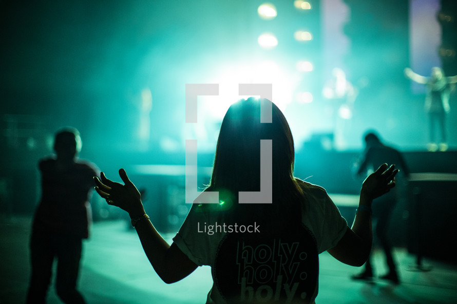 girl with holy holy holy t-shirt with raised hands during a concert 