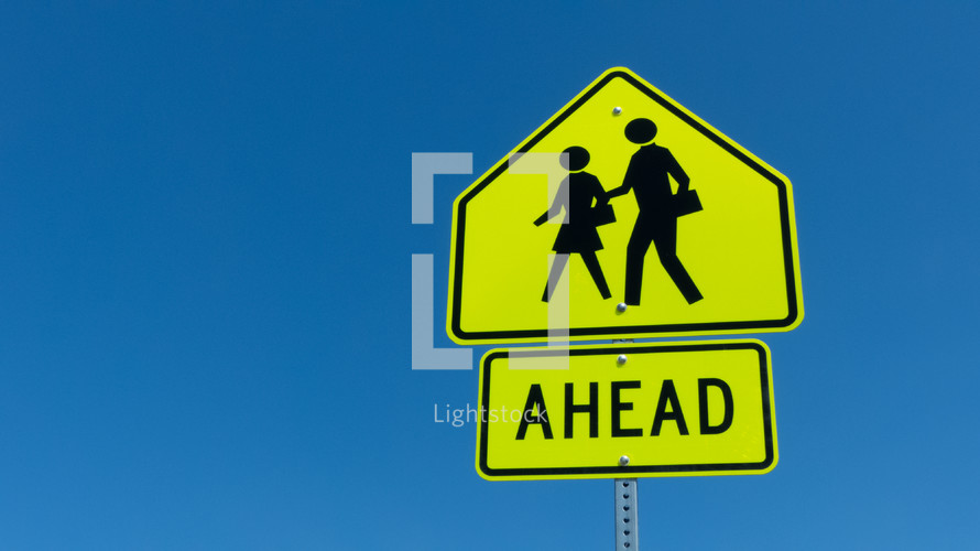 pedestrian crossing sign against blue sky with copy space - back to school, important reminder