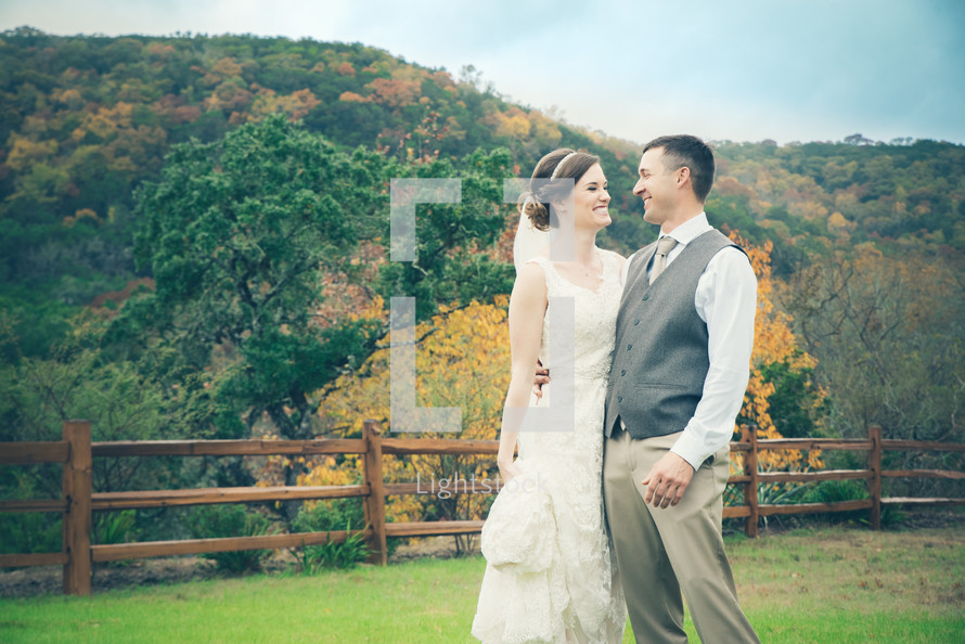 bride and groom standing in a pasture 