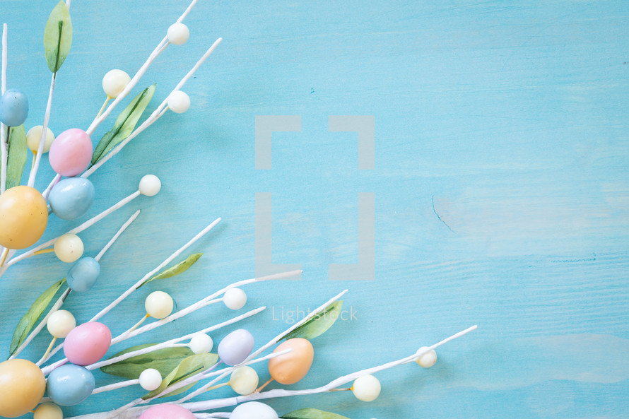 Sprigs of easter egg decor on a blue wood background with copy space
