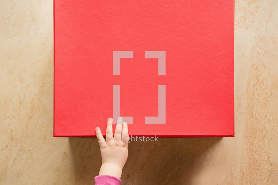 a girls hand on a red box 