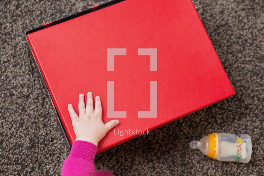 a girls hand on a red box 