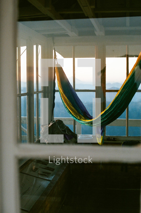 hammock on a deck overlooking fog over mountains at sunrise 