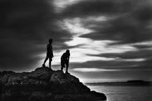 brothers climbing on rocks along a shore 