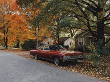 old car parked on a neighborhood street in fall