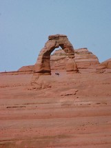 red rock arch and tourists 