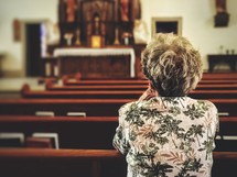 elderly woman praying alone in a church 