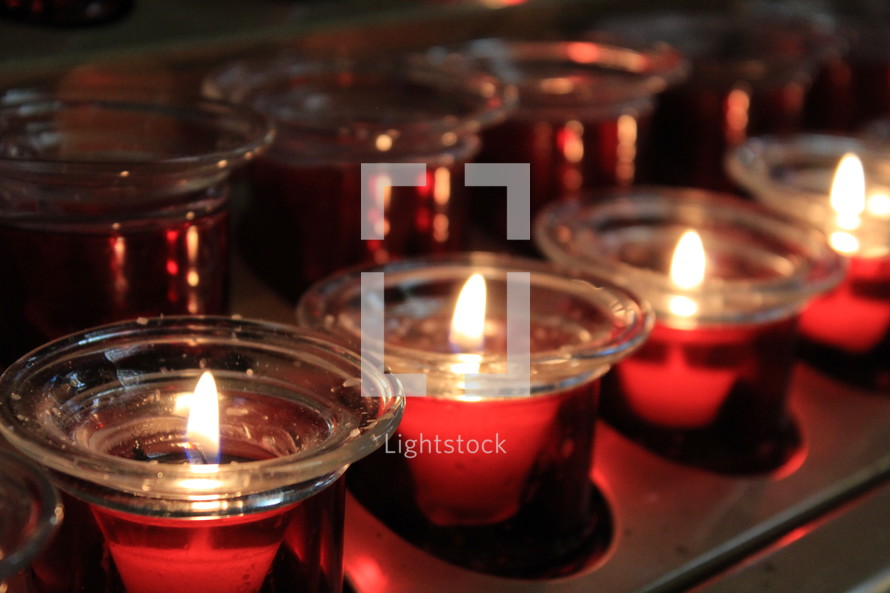 Rows of beautiful red Candles reflect the holidays and light up a church during a prayer vigil or Christmas Eve Service in a church during the Christmas season. 