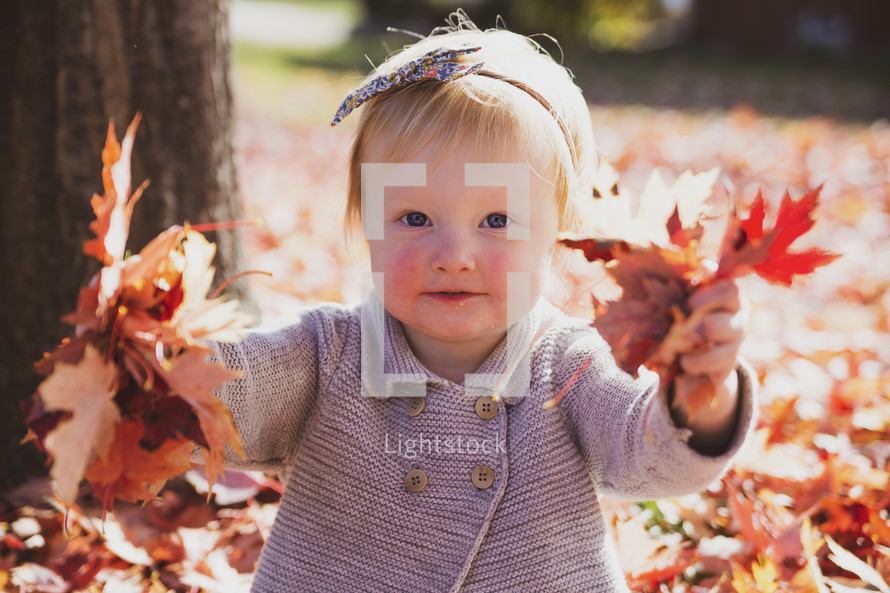 little girl playing in fall leaves 