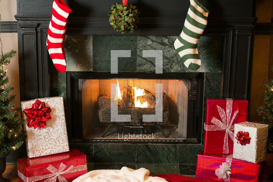 stockings and mistletoe hanging on a hearth and wrapped presents 